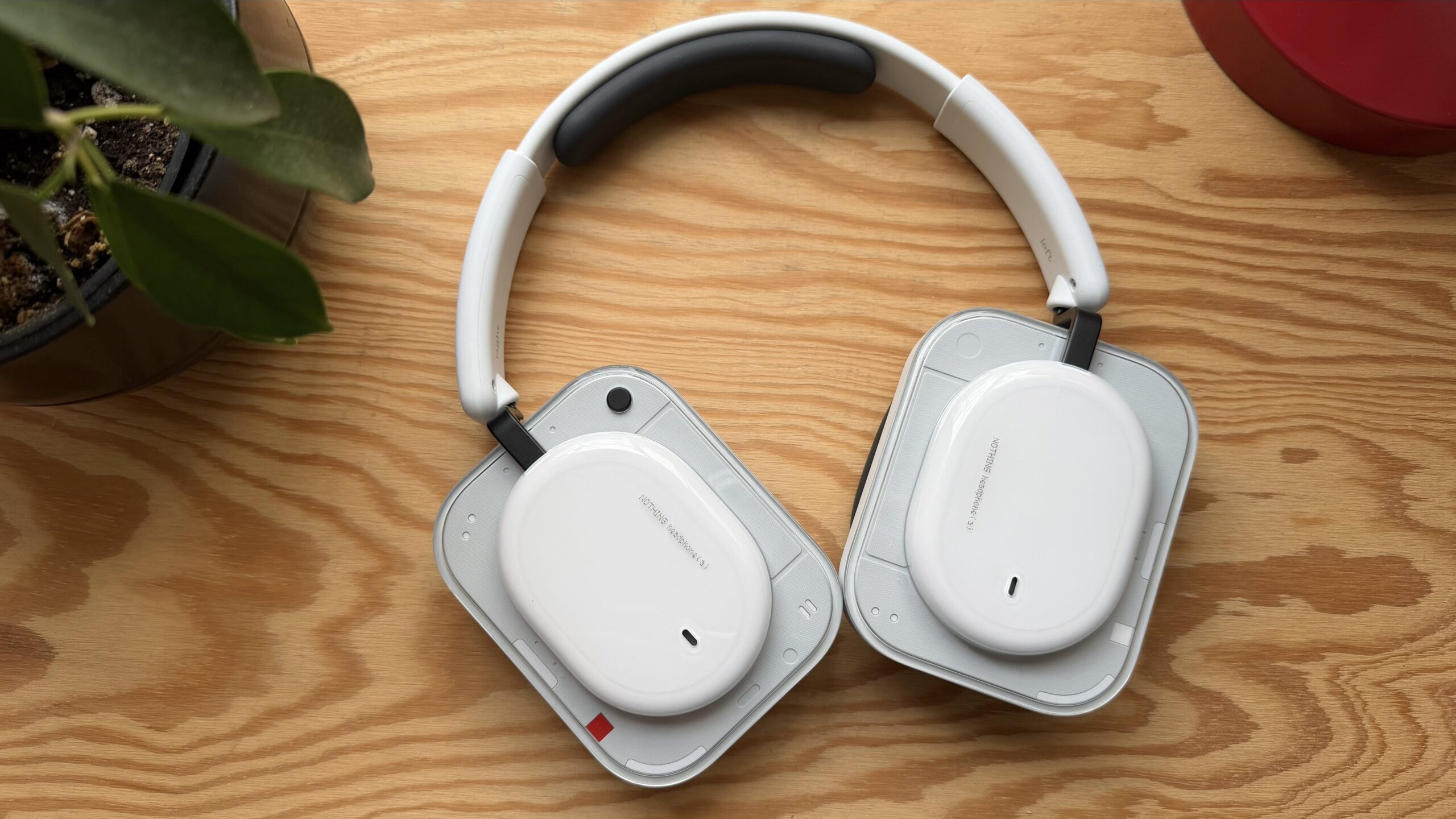 white nothing(a) headphones next to plant on wood tabletop