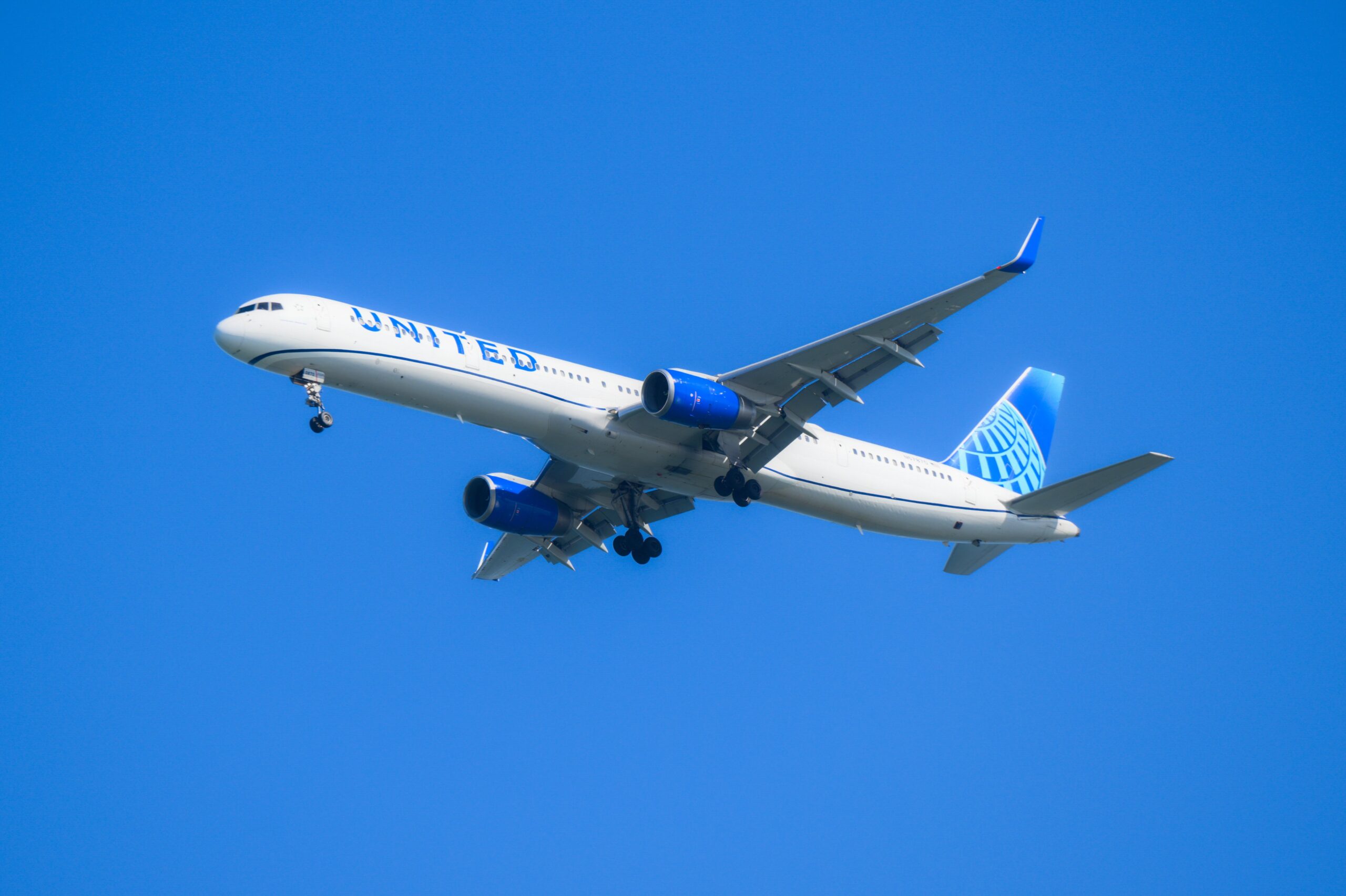 A United airplane flies across a blue sky.