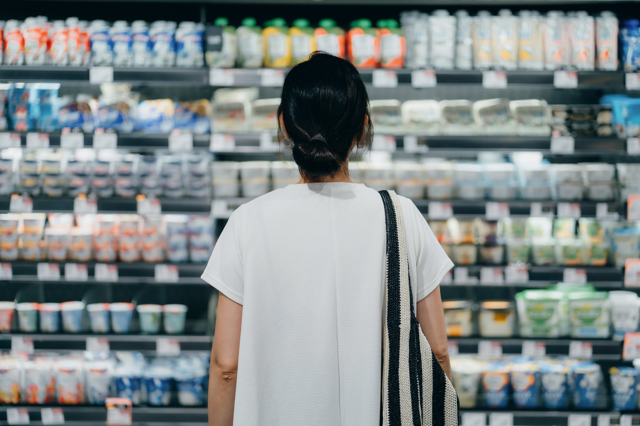 back of woman looking at dairy aisle at grocery store