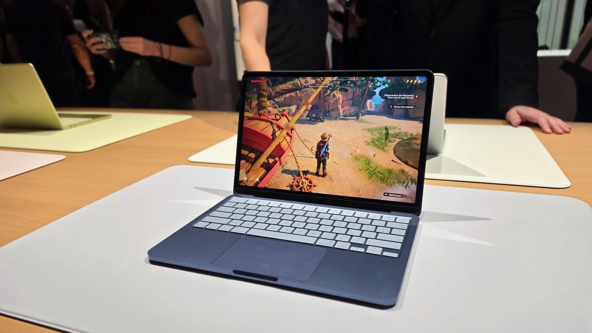 The Apple MacBook Neo laptop sitting on a desk with a game displayed on its screen.