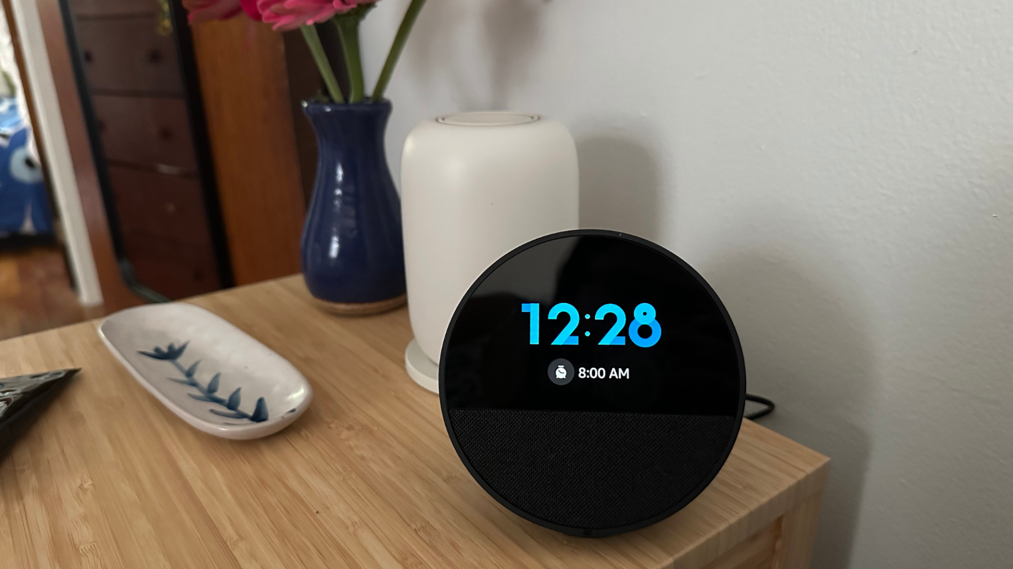 An Echo Spot sitting on a nightstand next to a lamp