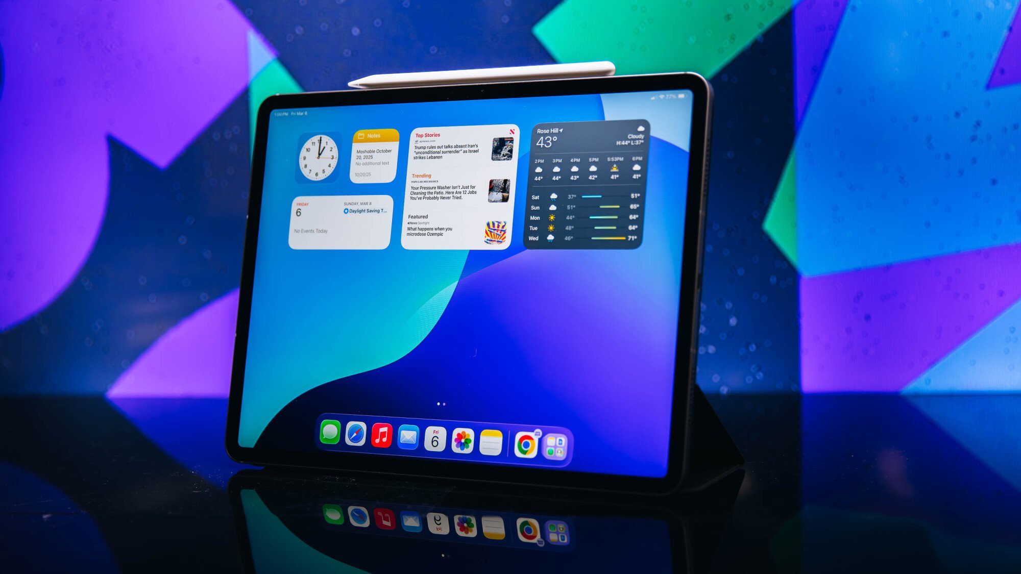 Apple iPad Air with Apple Pencil, sitting on a table with a colorful background.