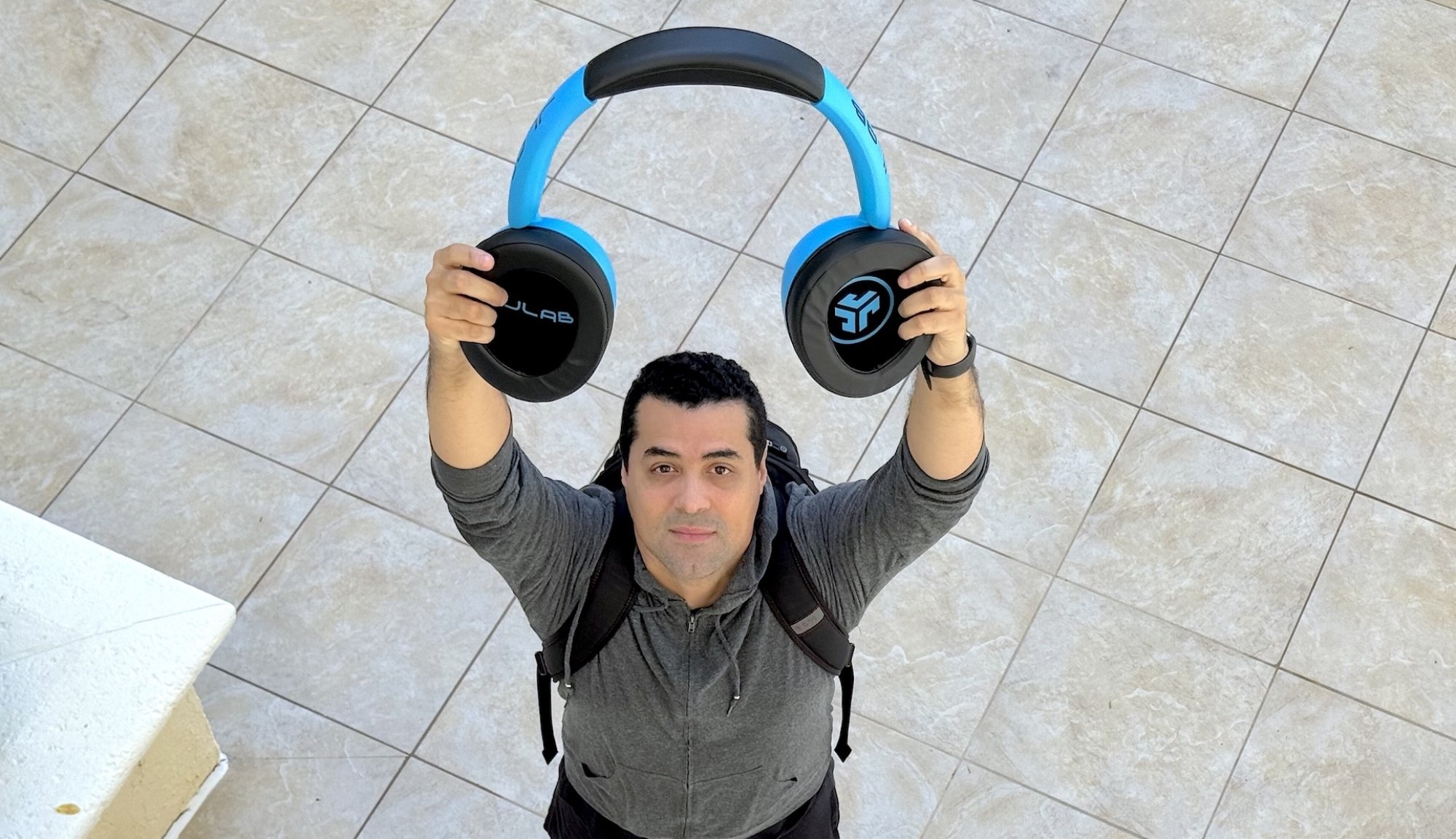A man holding giant headphones above his head