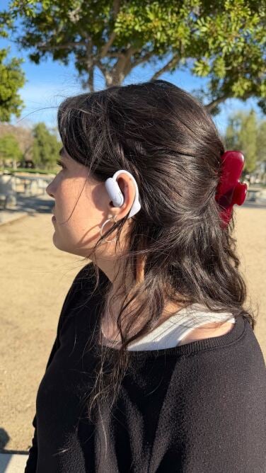 profile of woman sitting outdoors wearing soundcore aerofit pro 2 earbuds in in-ear mode