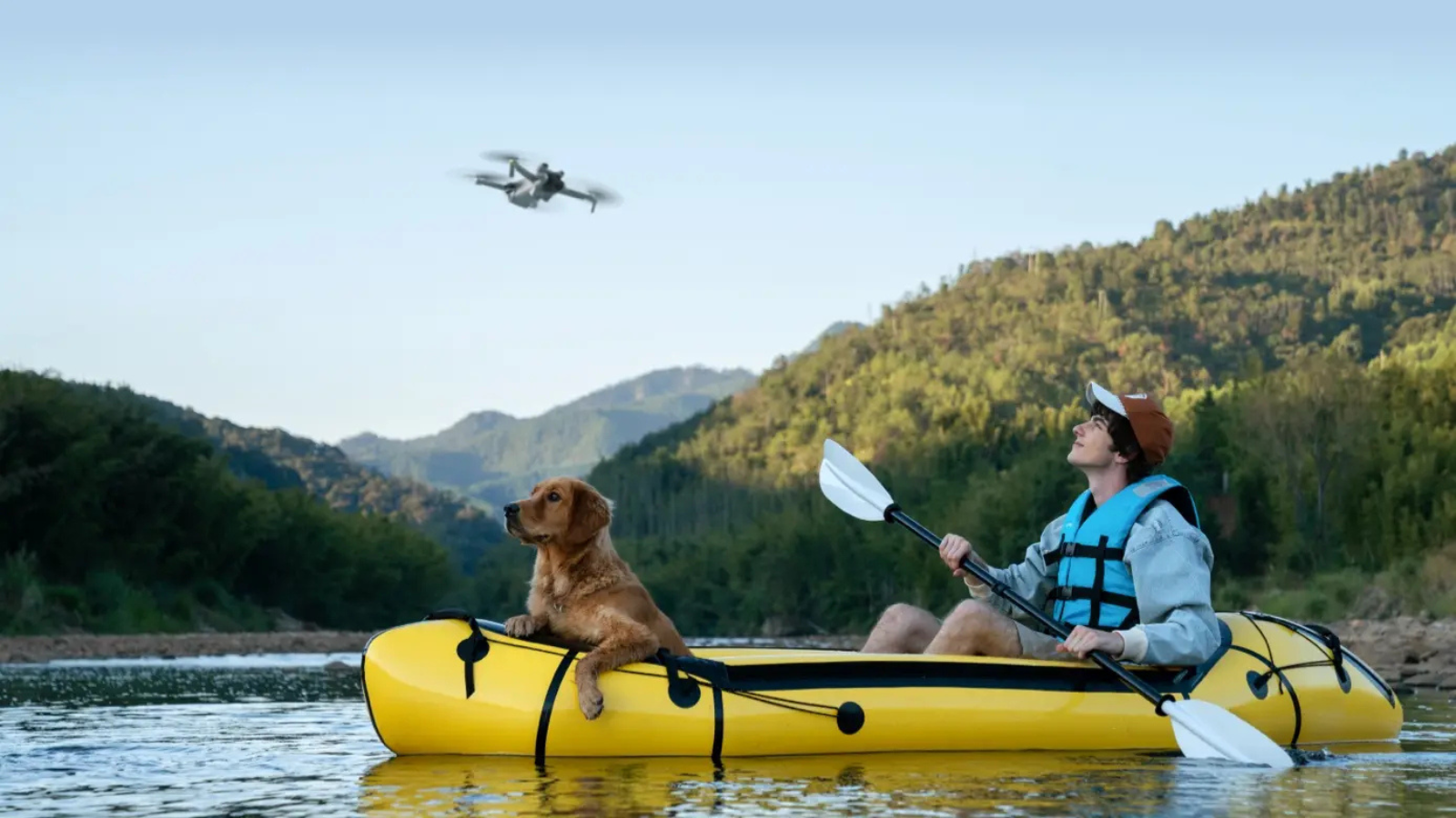 man and dog in kayak with DJI Mini 3 drone hovering overhead