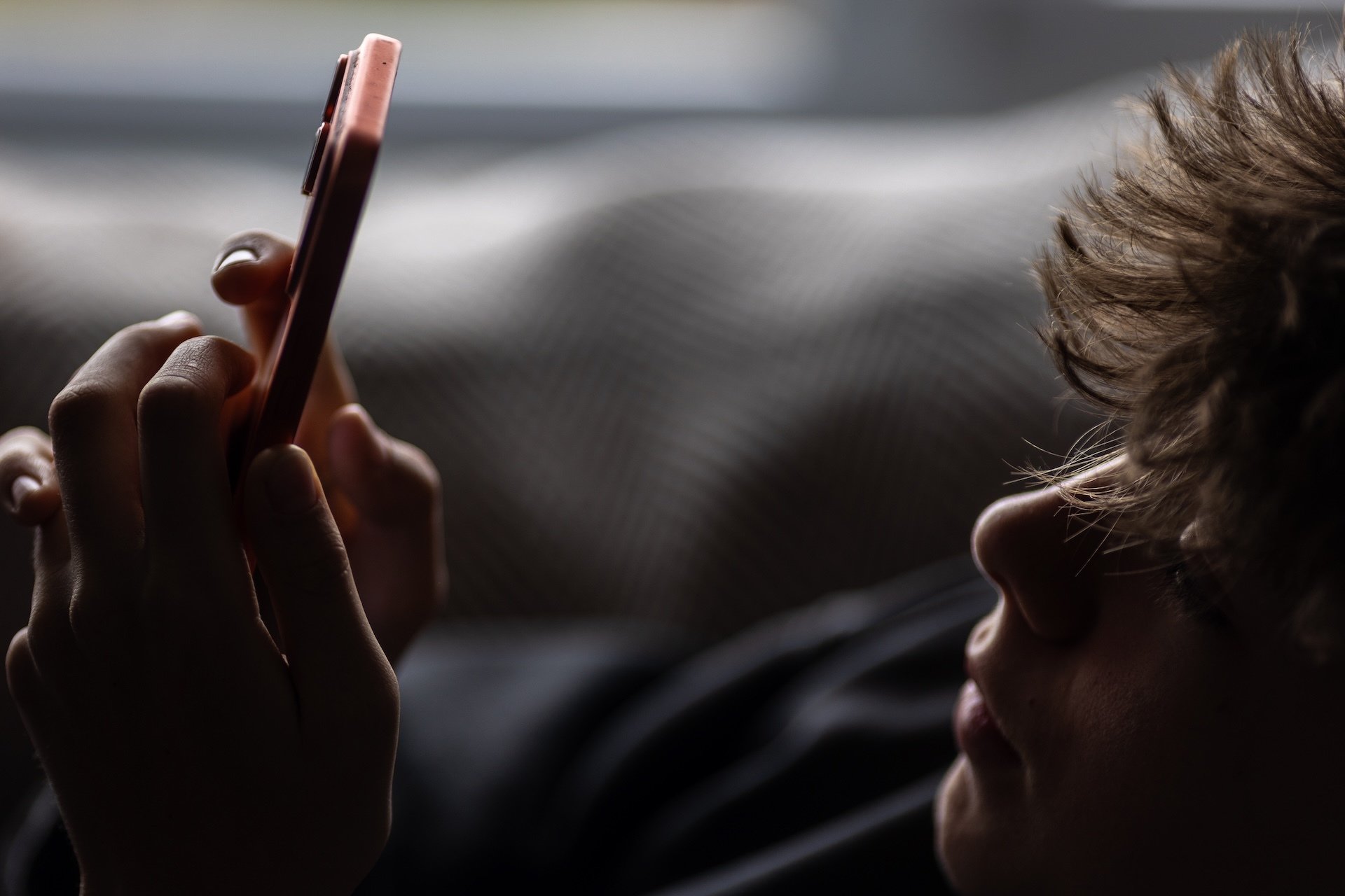 Teen boy looks at a phone.