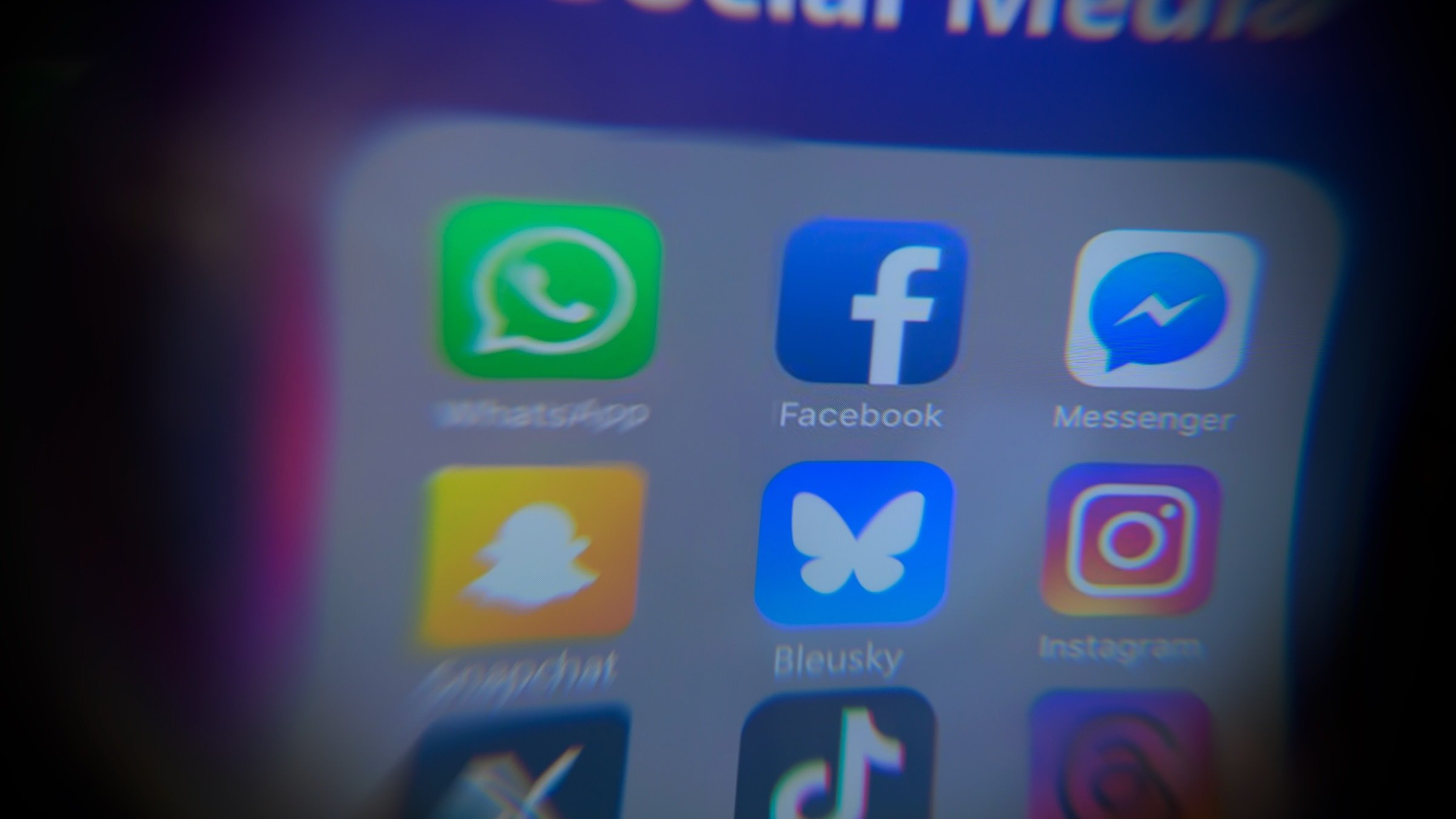blurry social media icons on iphone screen with Bluesky app in center
