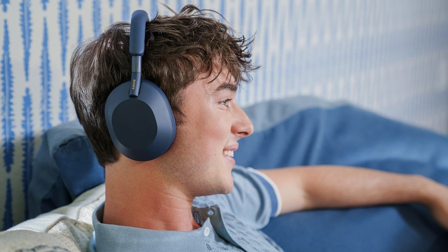 person sitting on couch wearing midnight blue sony headphones