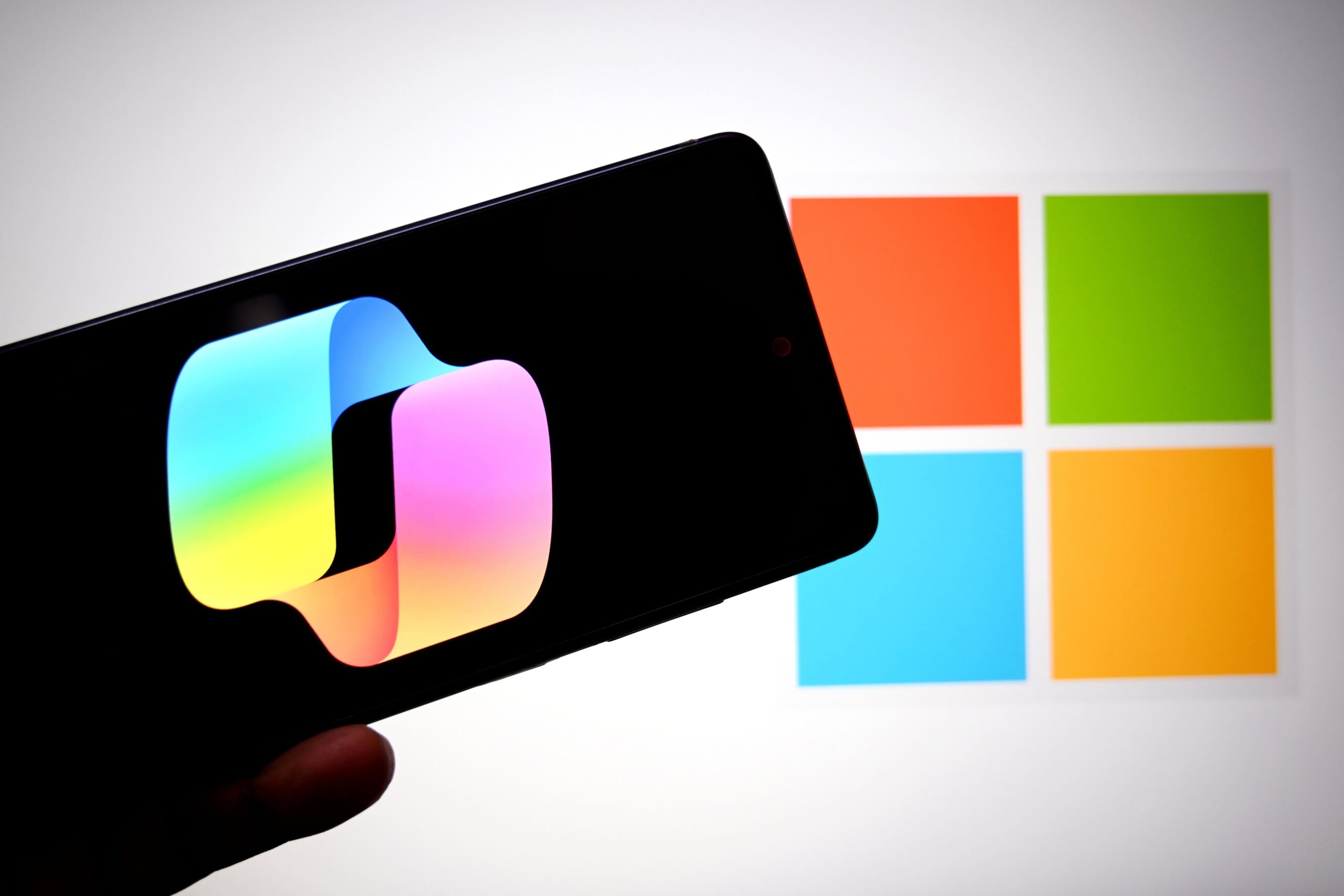 In this photo illustration, a Microsoft Copilot logo is seen displayed on a smartphone with a Microsoft logo in the background