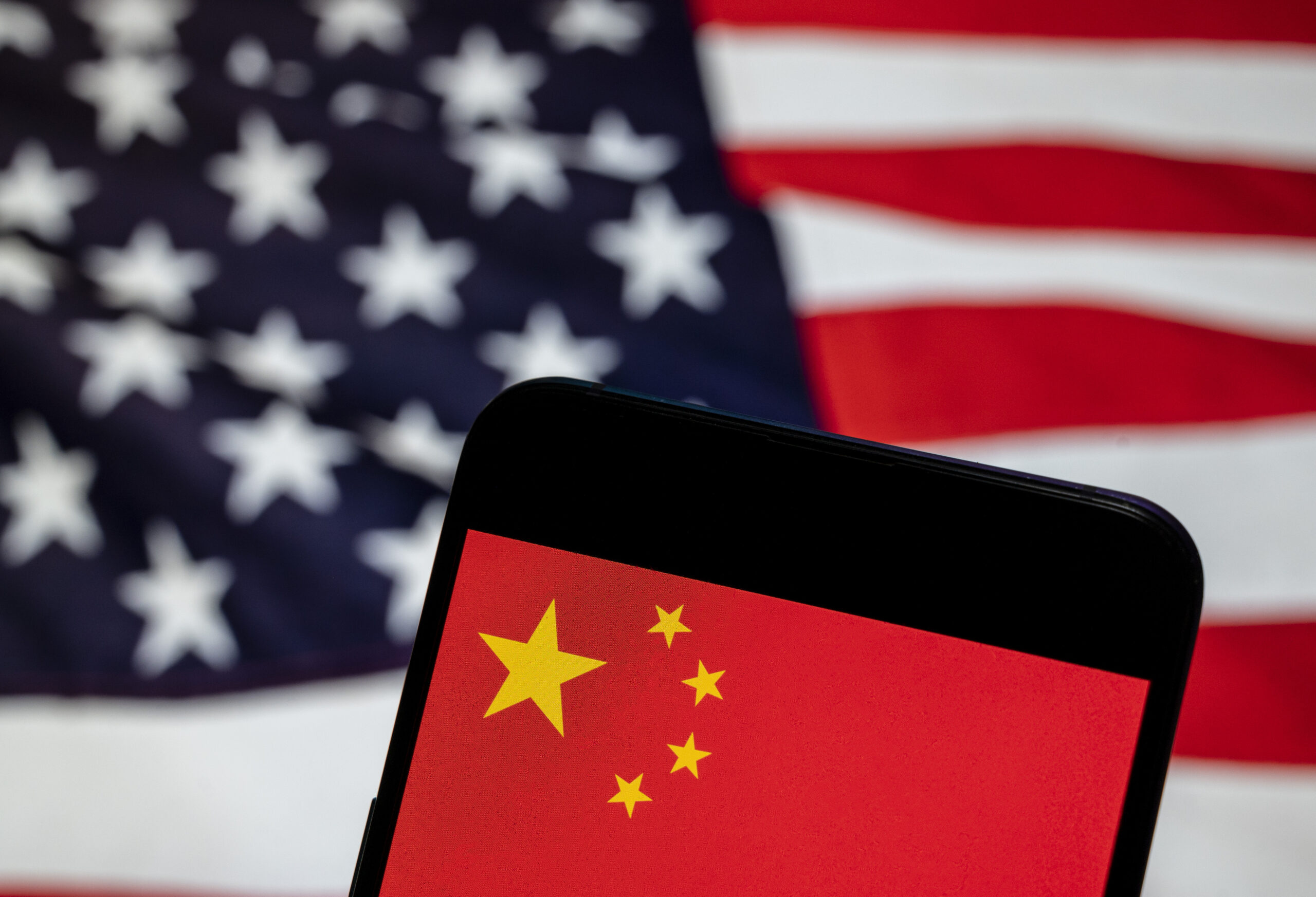 China flag on mobile device with U.S. flag in the background