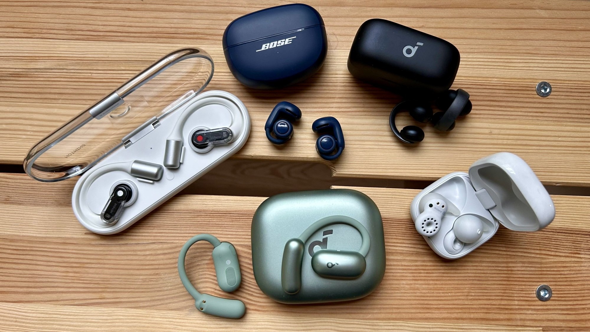 different pairs of open earbuds on wooden bench