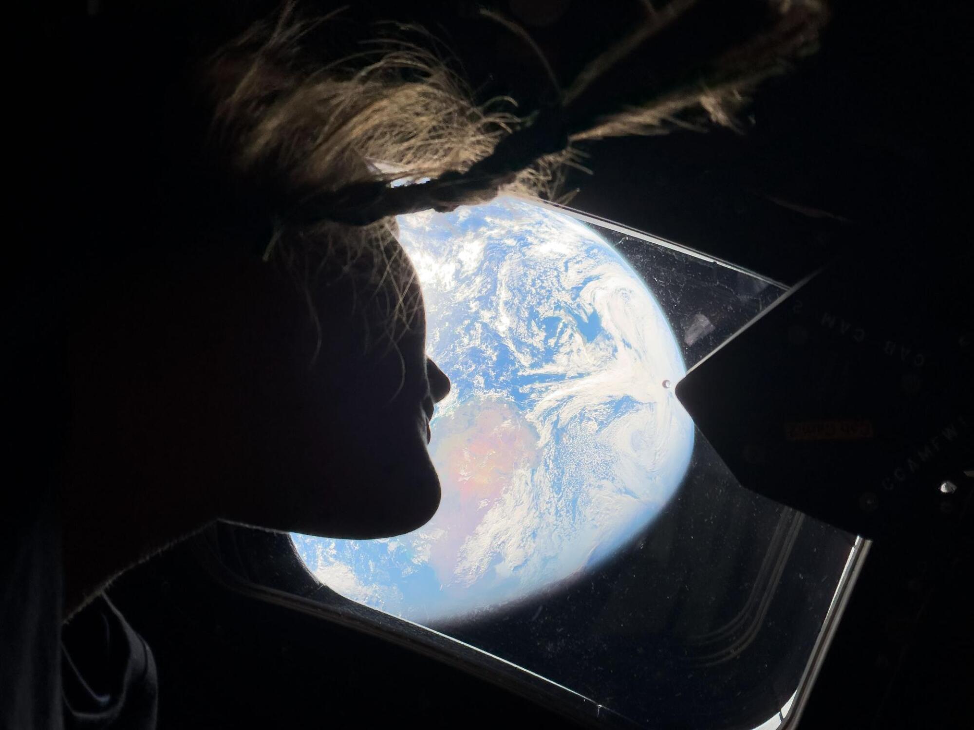 NASA astronaut and Artemis II mission specialist Christina Koch peers out of one of the Orion spacecraft's main cabin windows