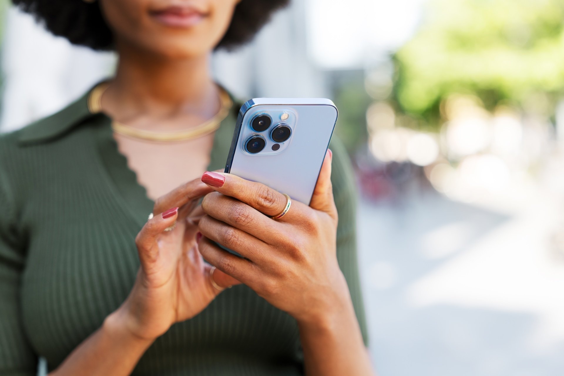 Woman holds cell phone in hand while she looks at it.