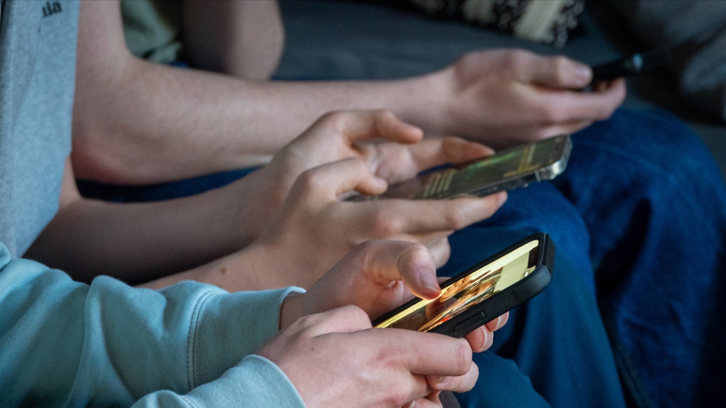 Three teenage boys look at their smartphone screens