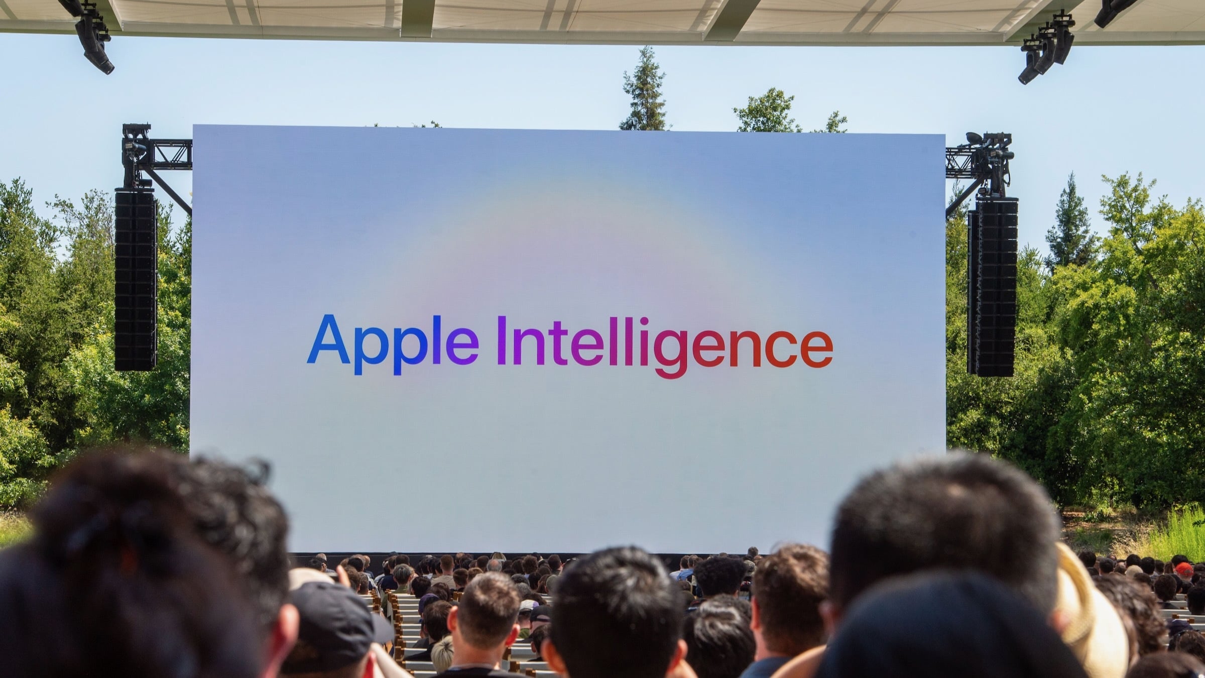 'apple intelligence' appears on video screen during WWDC 2025 in front of a packed crowd