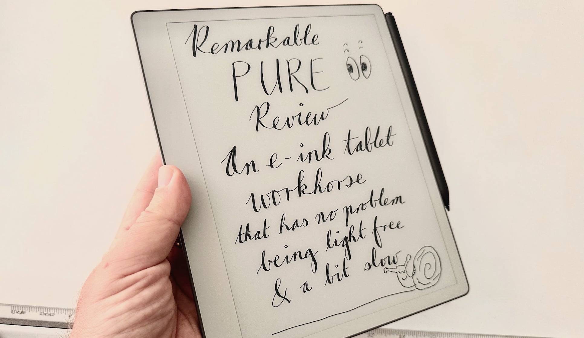 An e-ink tablet with handwriting on it held in a hand