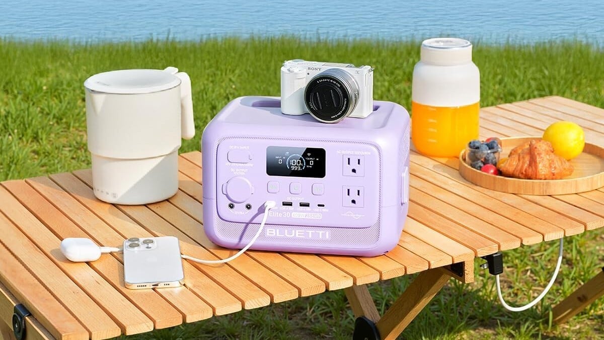a Bluetti Elite 30 V2 sits on a picnic table outside while recharging a camera 