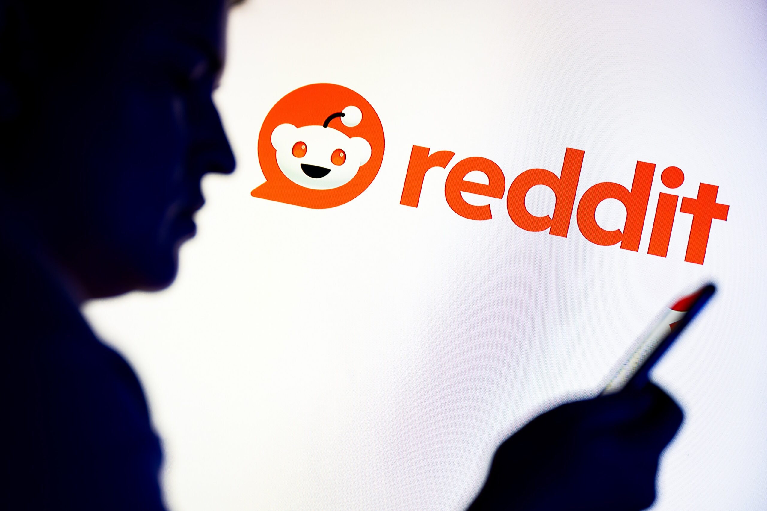 Reddit logo with smartphone user in the foreground