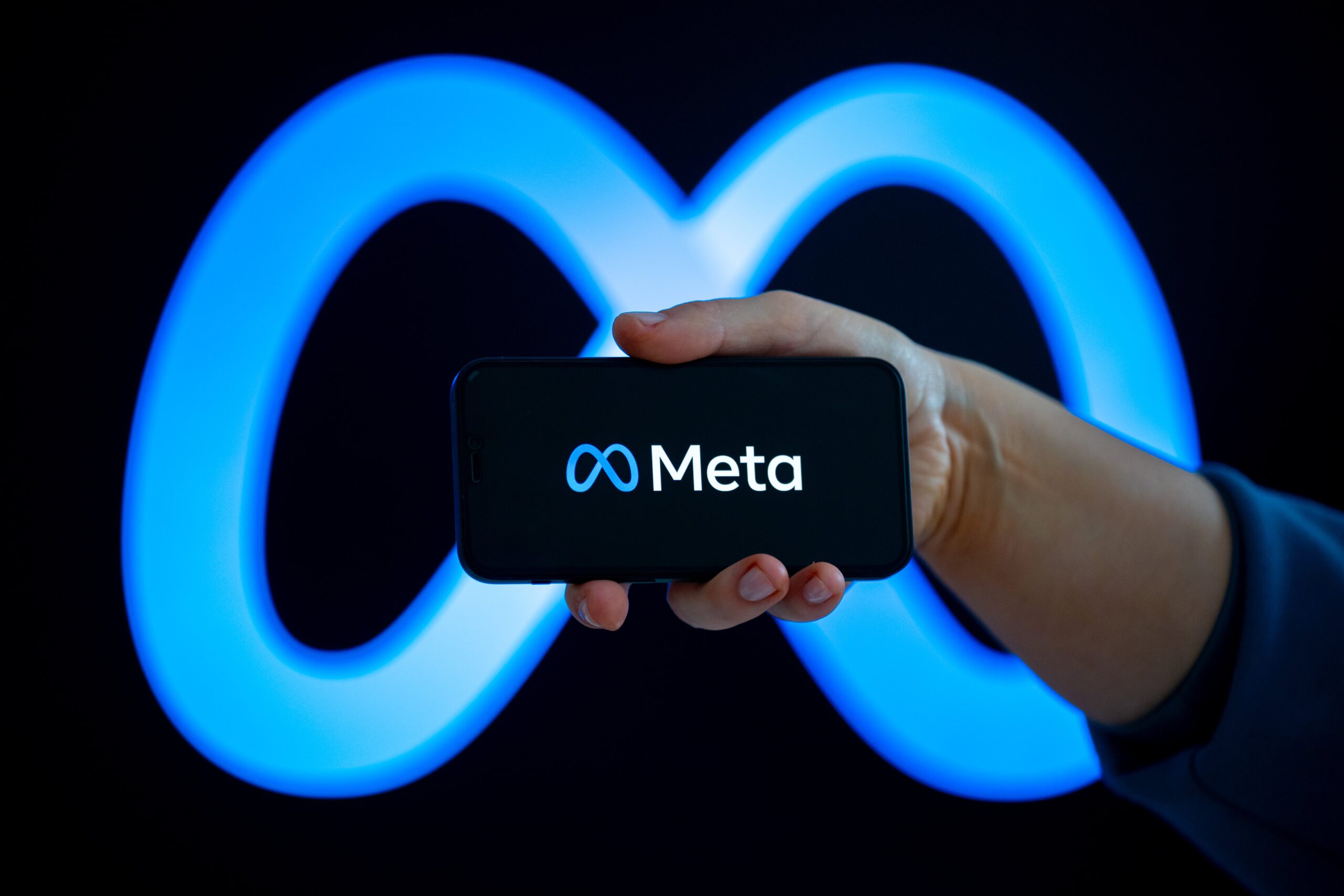 meta logo on smartphone with same logo in the background
