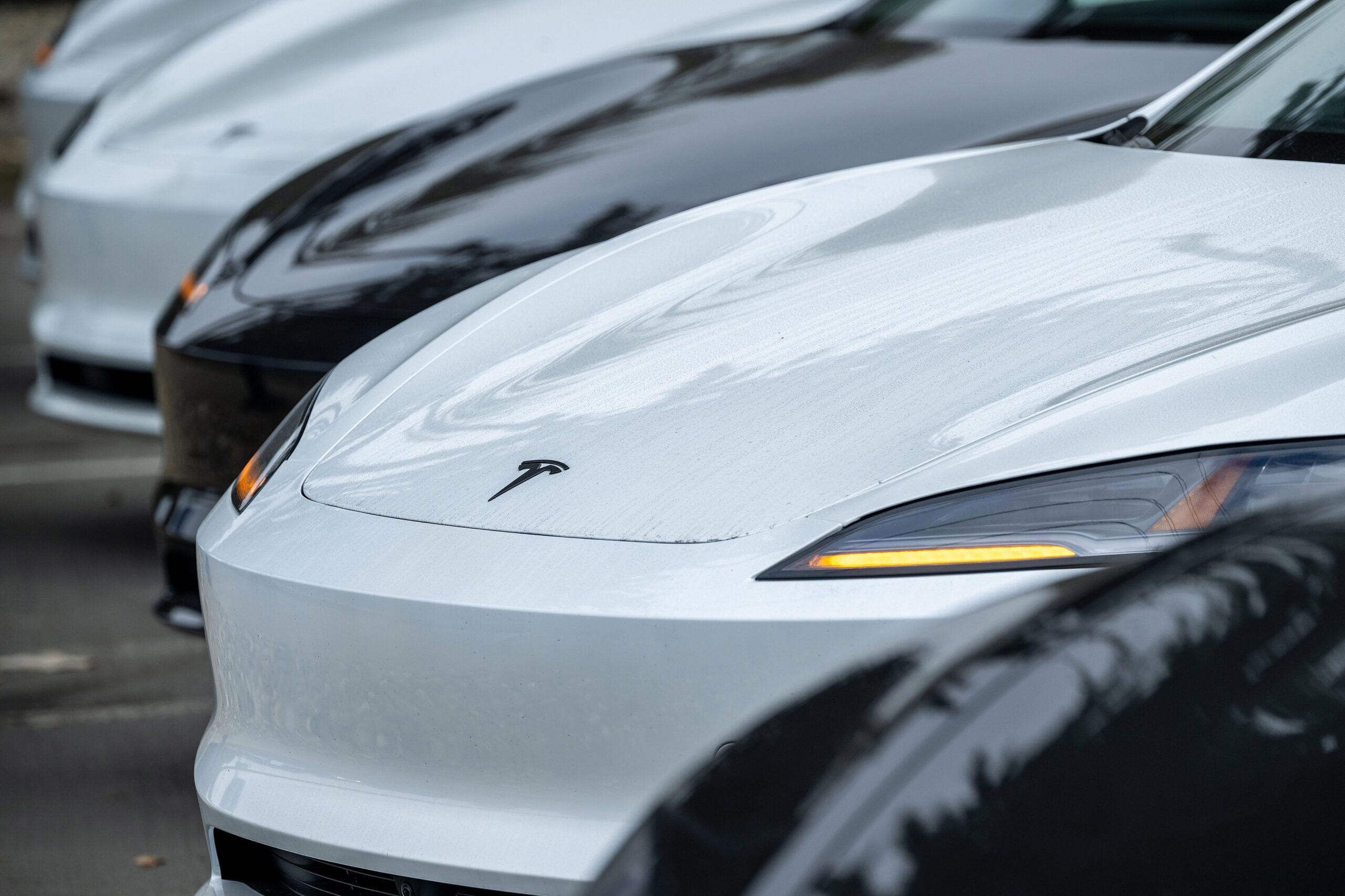 A row of Tesla vehicles in a parking lot.