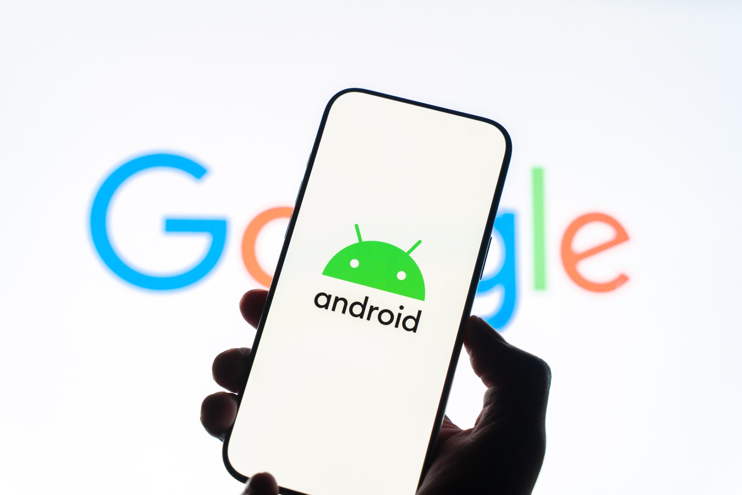 Android logo on mobile device with Google logo in the background