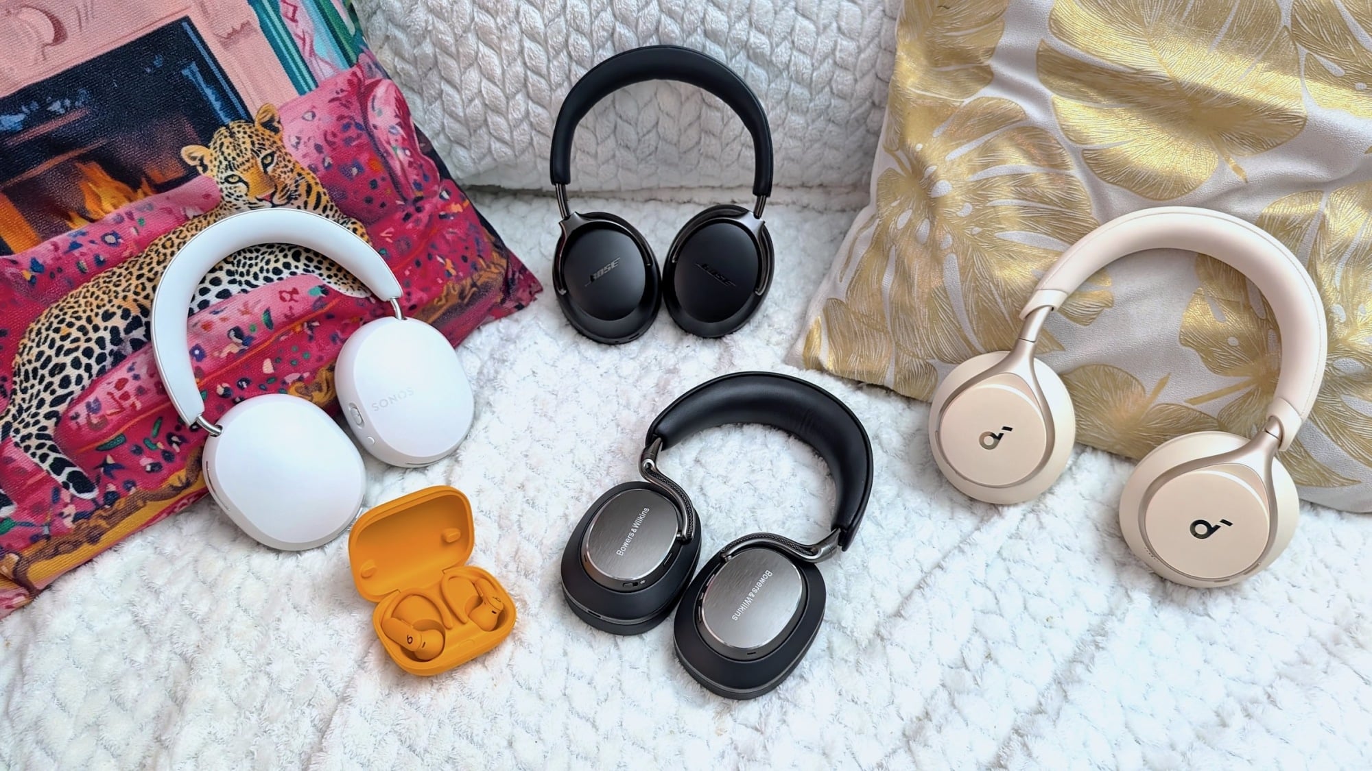 sonos, bose, beats, bowers and wilkins, and anker headphones on a bed