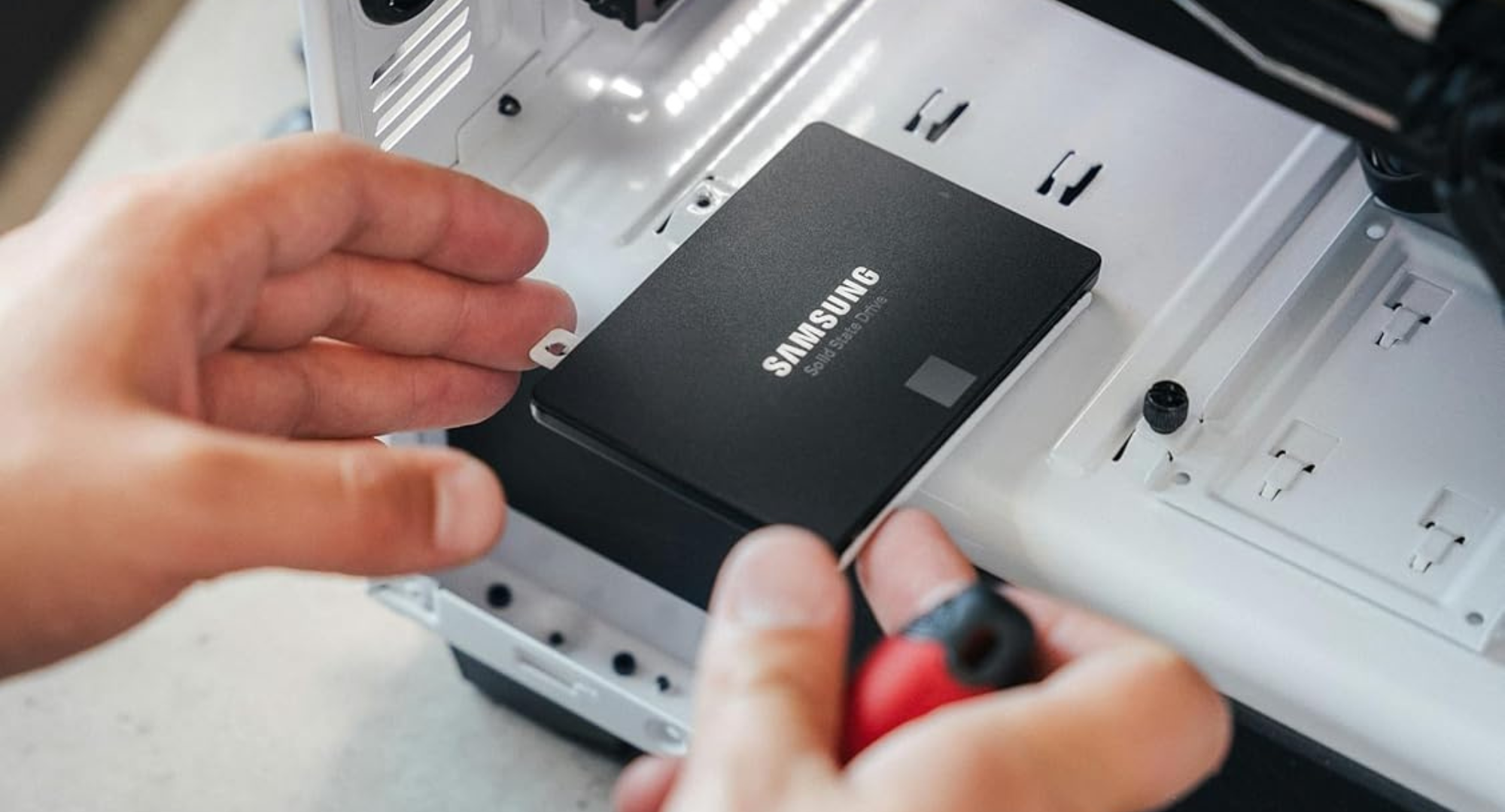A hand reaching out to insert a Samsung Electronics 870 EVO 2TB SSD.