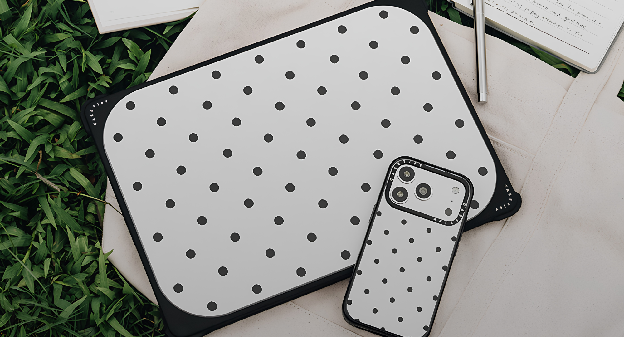 A MacBook in a Casetify sleeve and iPhone in a Casetify case sitting on the grass. 