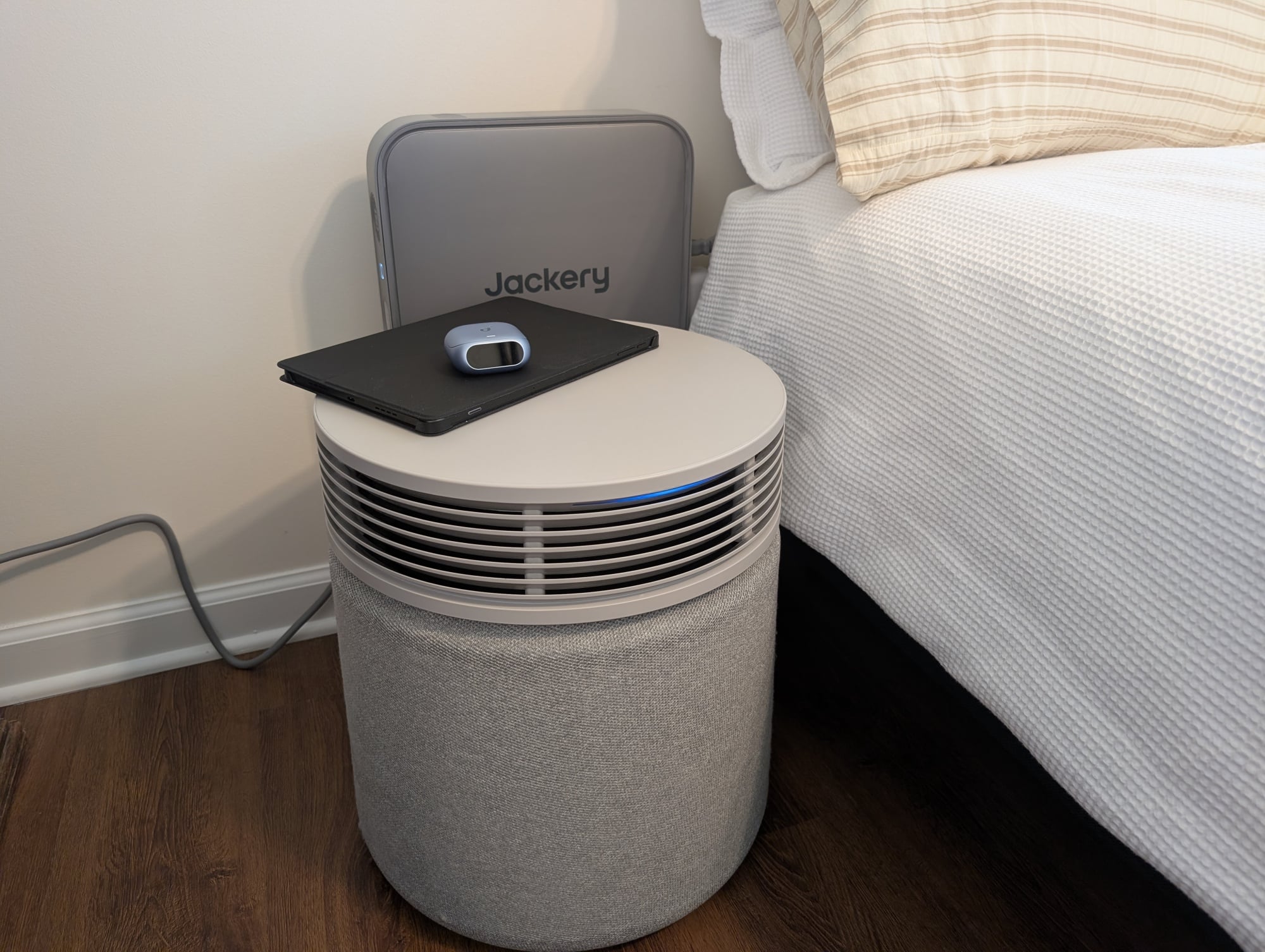 the Jackery FridgeGuard behind an air purifier next to a bed.
