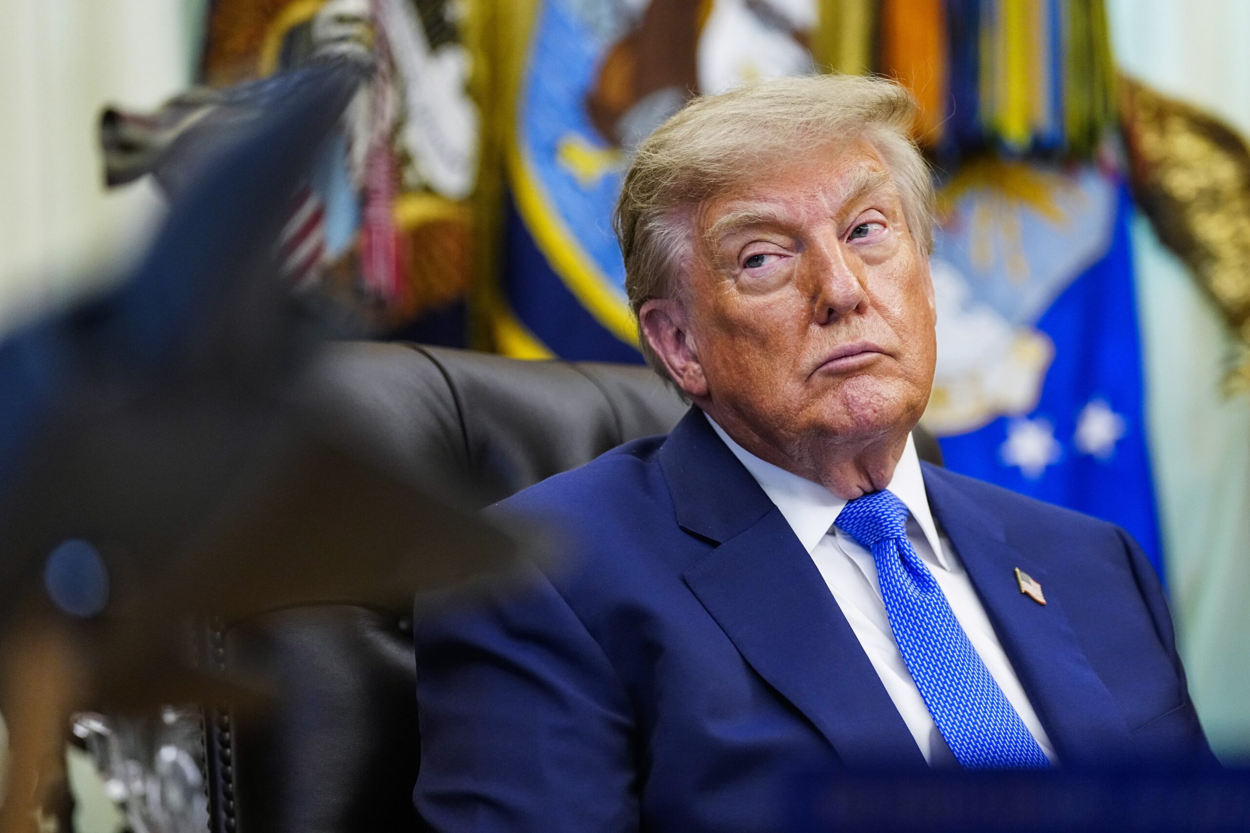 Trump sits in the Oval Office, staring off to the side.