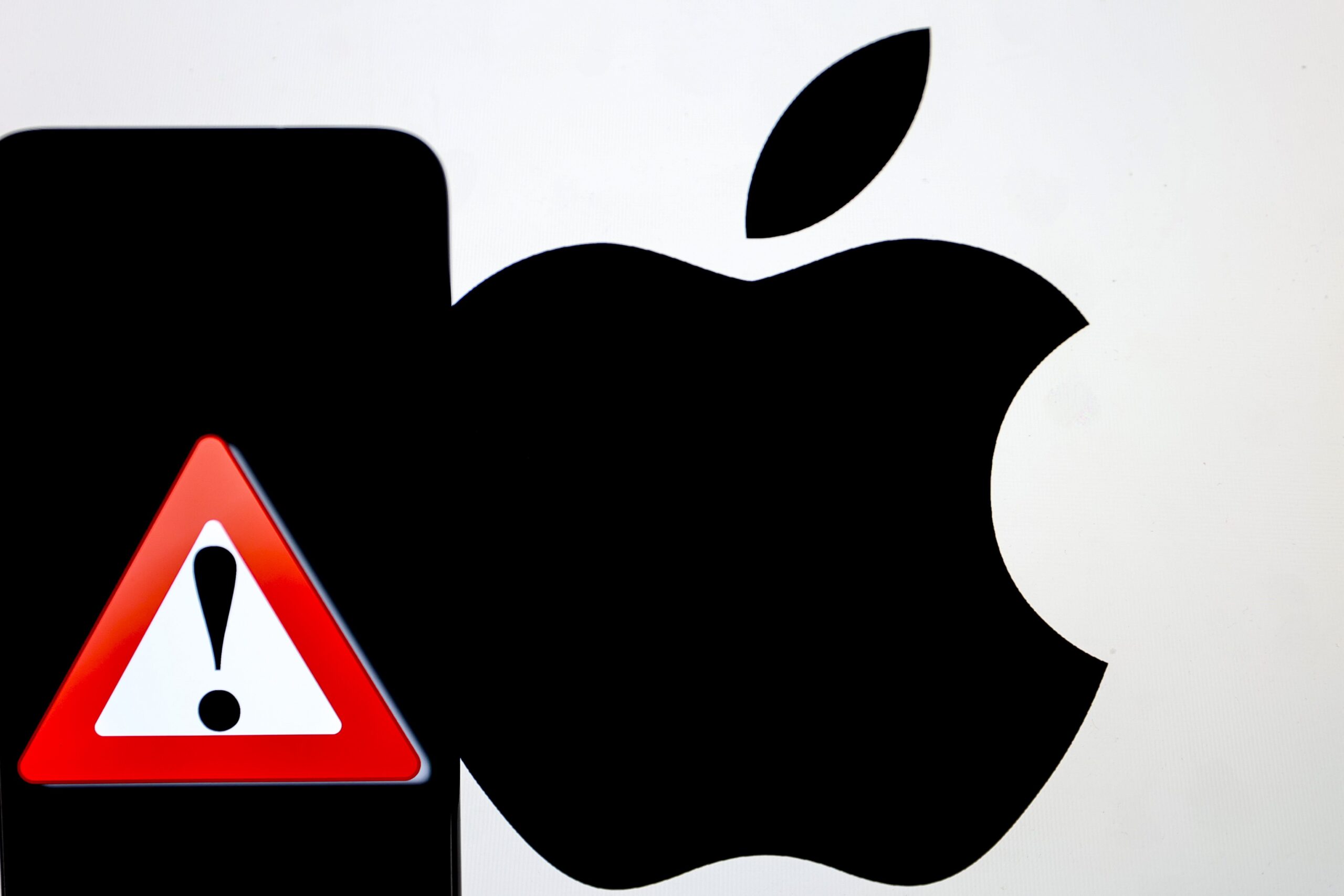 A dark iPhone screen displaying a bright red triangle with an exclamation point inside. Behind it is the Apple logo. 
