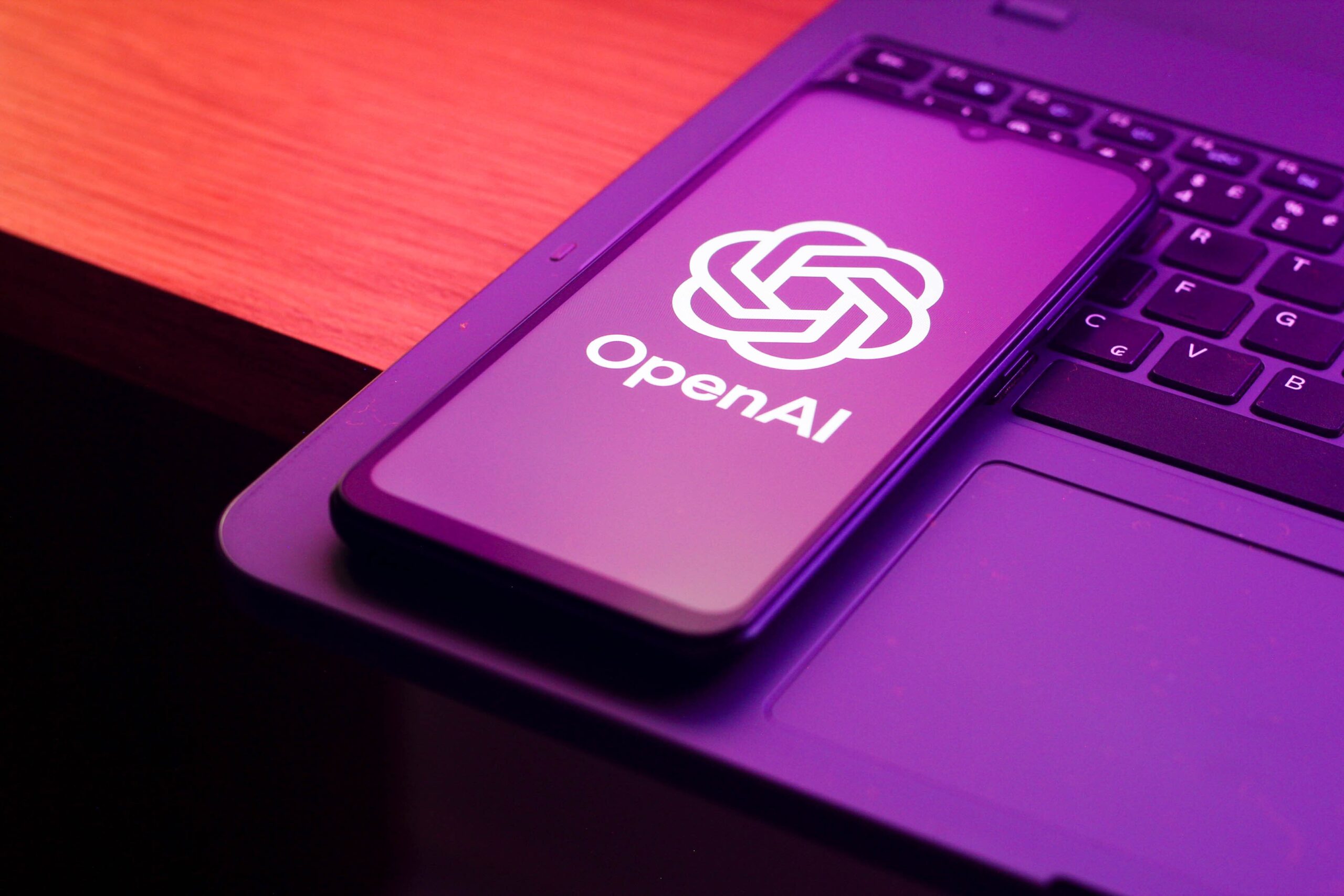 the OpenAI (Open AI - Chat GPT) logo is seen displayed on a smartphone screen.