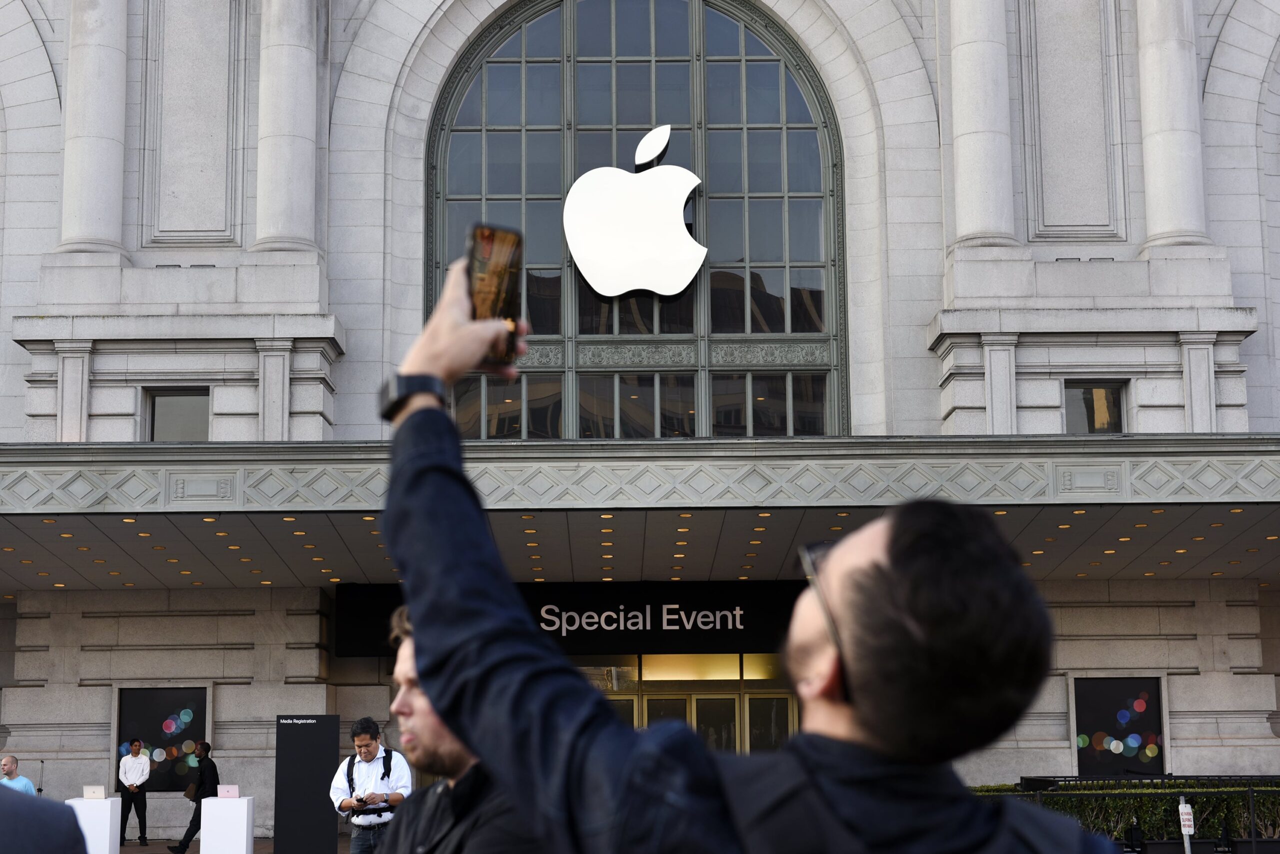 An attendee takes a photograph with a mobile device outside of the Bill Graham Civic Auditorium before the start an Apple Inc. event