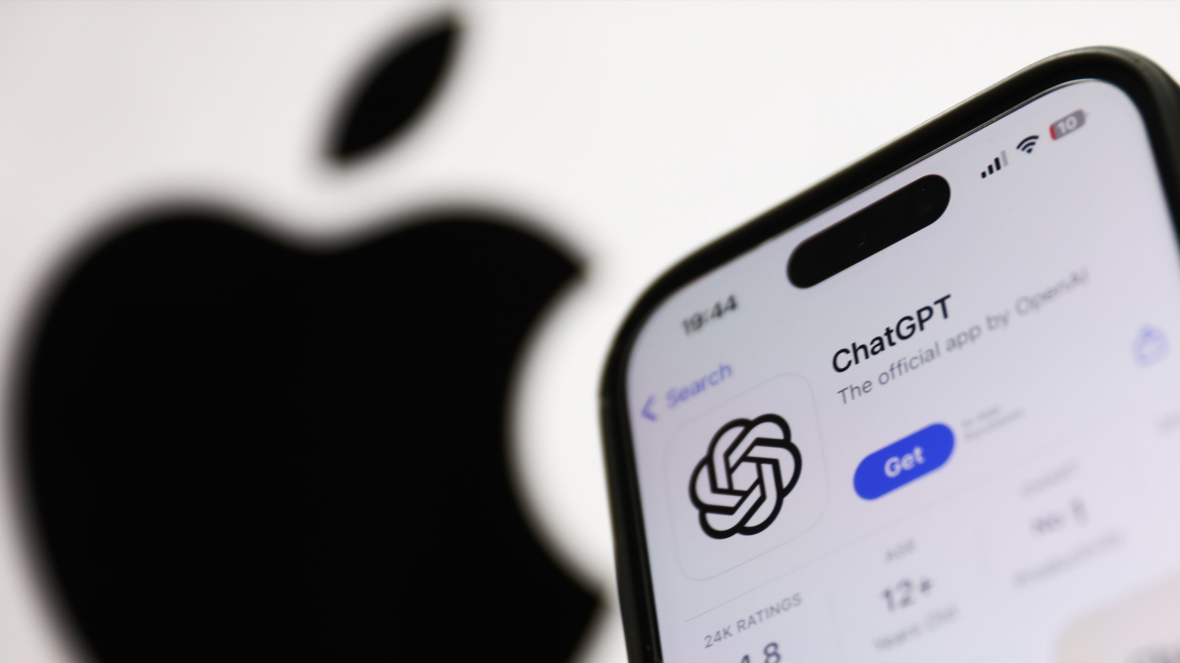 ChatGPT on AppStore displayed on a phone screen and Apple logo dislpayed on a screen in the background