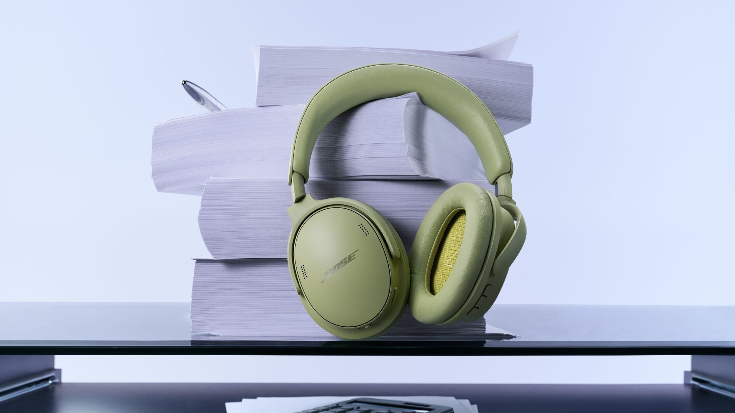 eucalyptus green headphones stacked against books on desk
