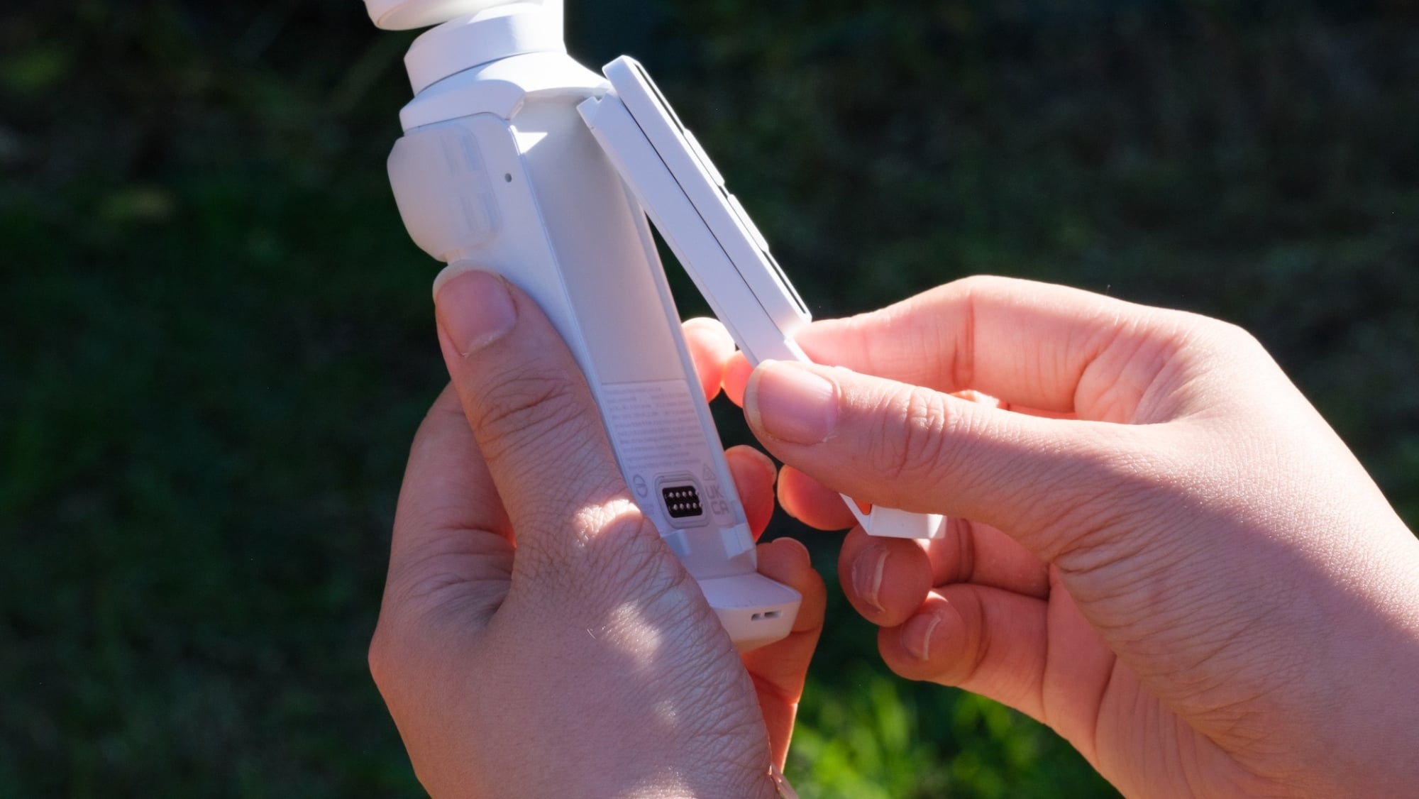 Hands attaching the Insta360 Luna Ultra's remote to its body.