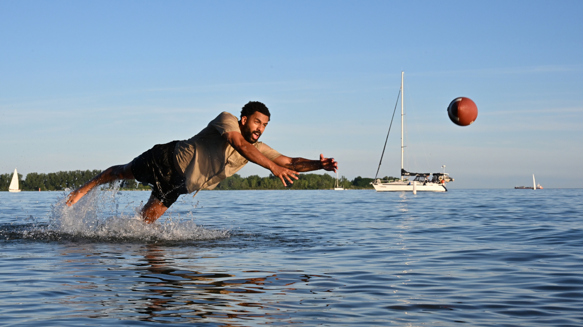 A man standing in water, diving for a ball.