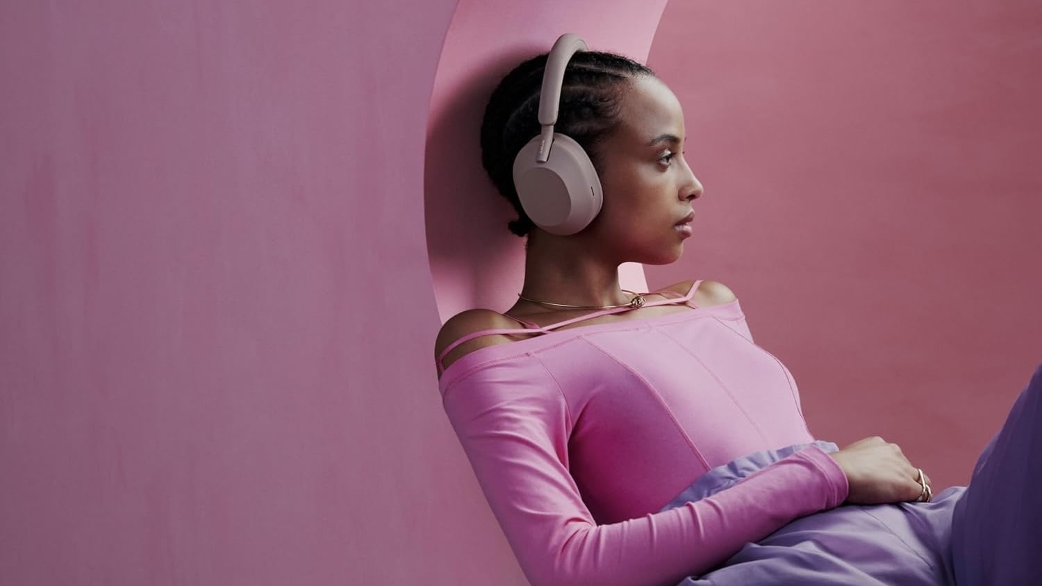 person wearing pink shirt and pink sony xm5 headphones in pink room