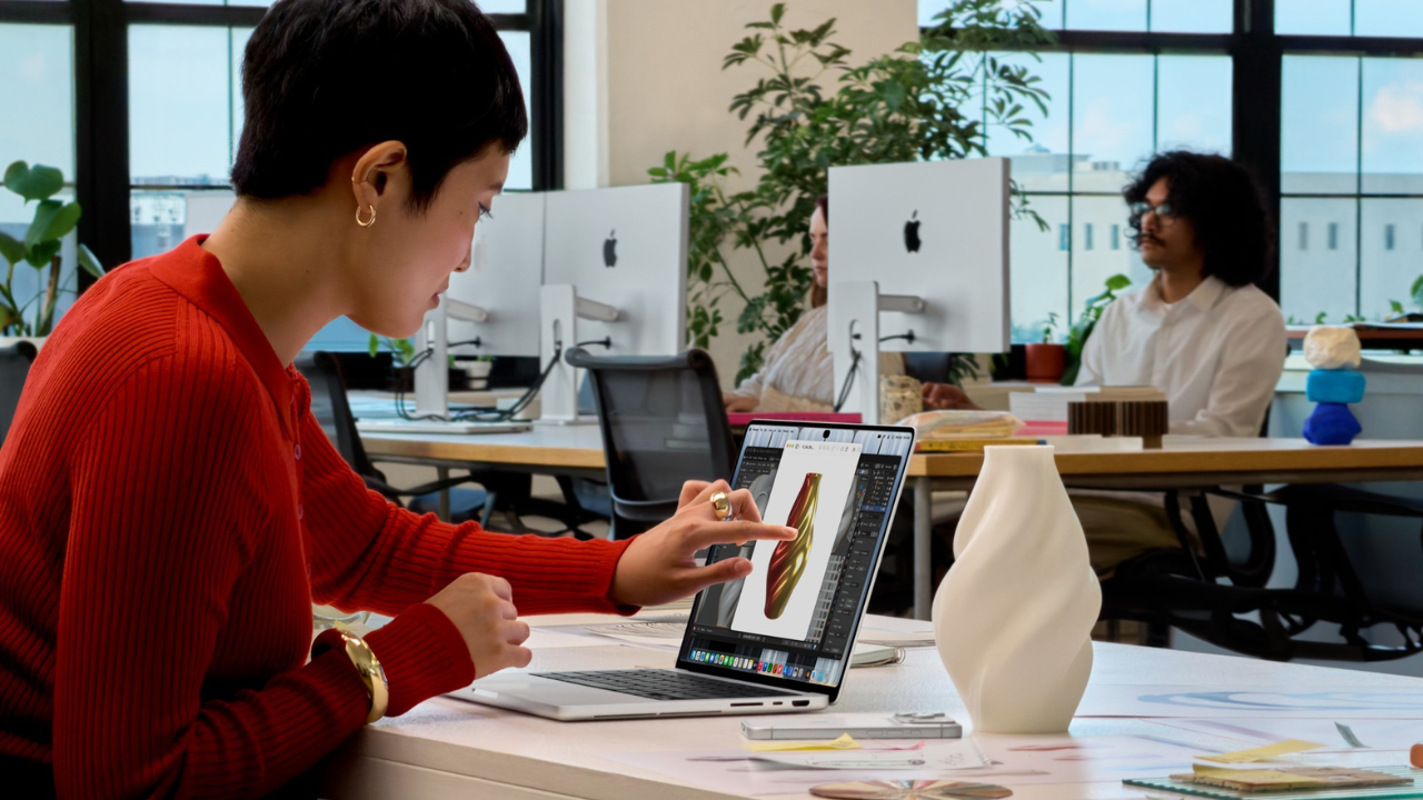 woman touching MacBook screen with pottery on a table