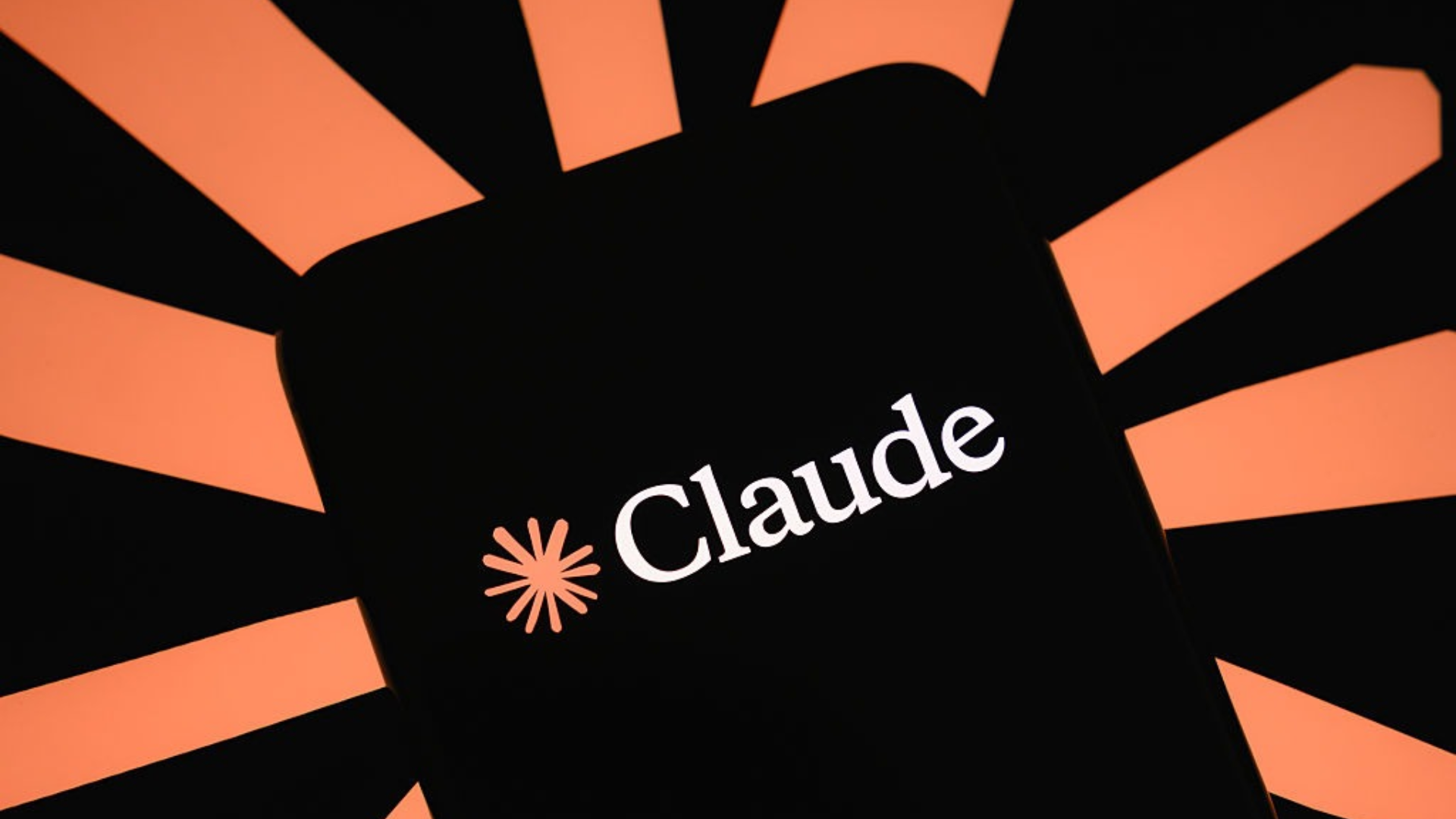 The Claude logo is displayed on a smartphone screen with the company's logo in the background.