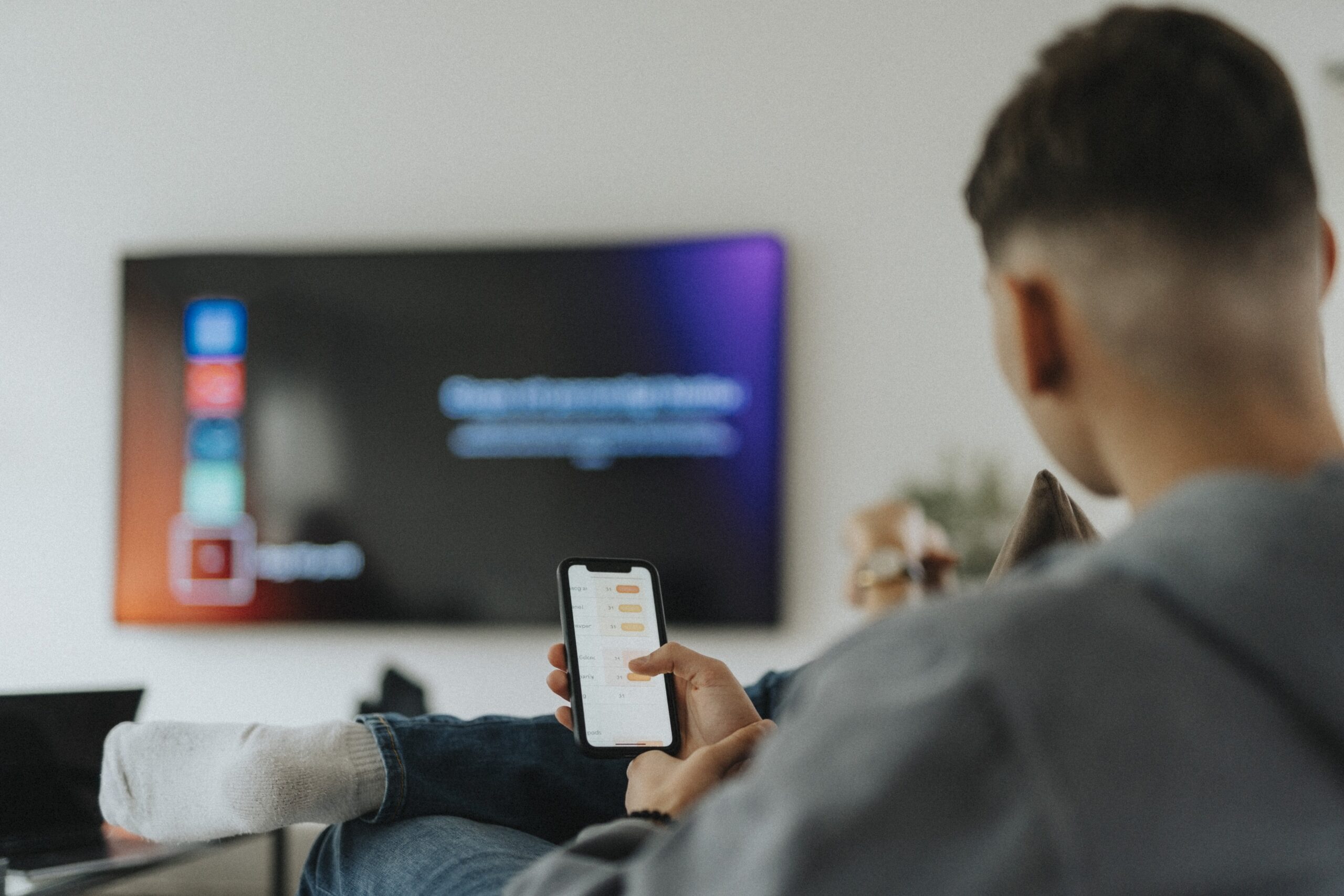 Teenage boy with smart phone app sitting in living room at home. 